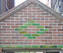 Pattern of green glazed brick against flat red bricks